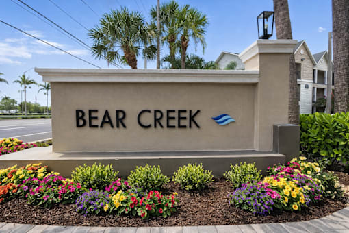 A sign that says Bear Creek stands in front of some buildings.