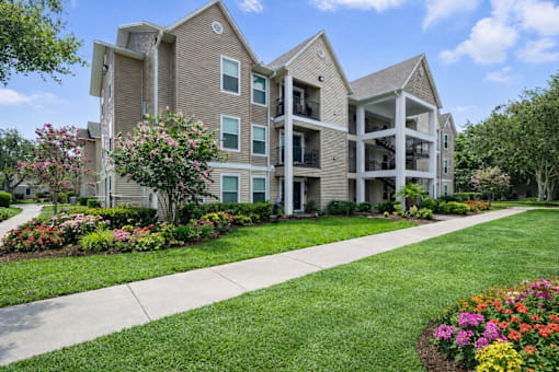 A large apartment complex with a well-maintained lawn and flower beds in front.