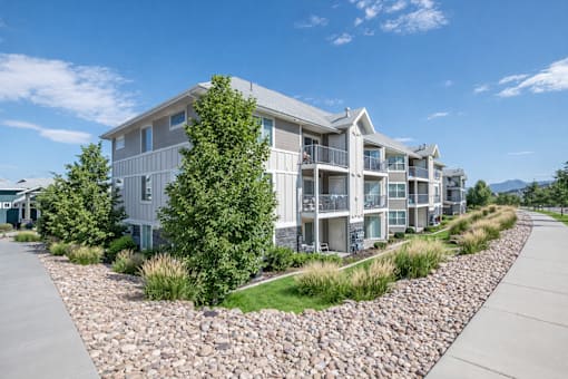 A modern apartment complex with a gravel driveway in front.