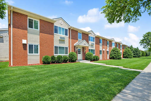 A row of red brick apartment buildings with green lawns in front.