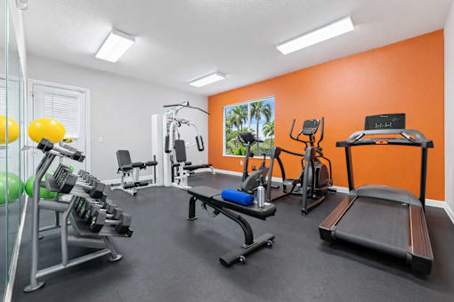 A gym with orange walls and a variety of equipment.
