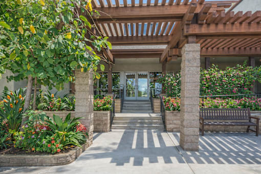 A building entrance with a bench and a tree.