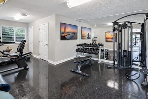 A spacious gym with a variety of equipment including treadmills, weights, and a squat rack.