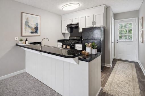 A kitchen with a black fridge and stove top oven.