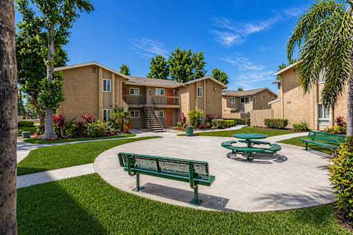 A sunny day at a residential complex with a green bench and picnic table.