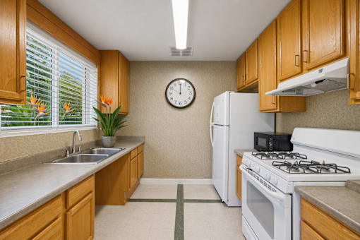 A kitchen with a white refrigerator, a white stove, and a clock on the wall.