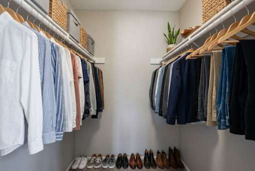 A closet with clothes and shoes neatly arranged.