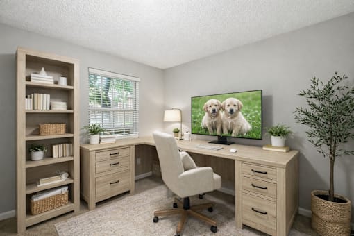 A room with a desk, chair, and a TV displaying two dogs.