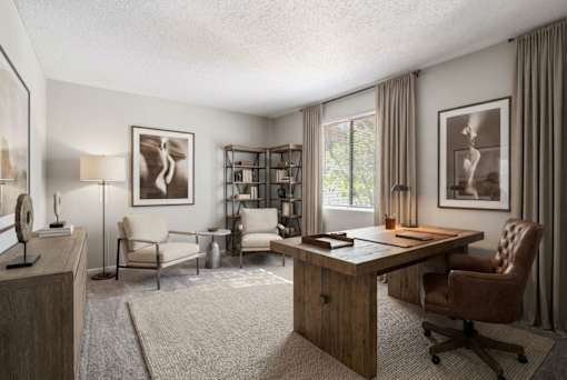 A well-lit room with a desk, chairs, and a bookshelf.