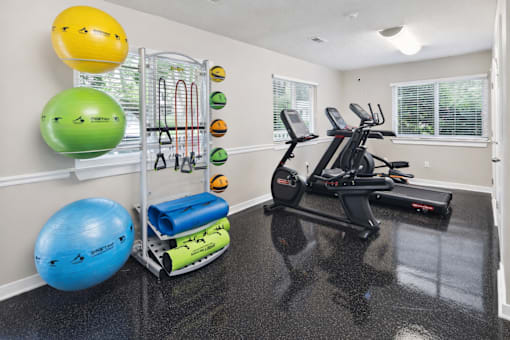 A home gym with a treadmill, exercise balls, and resistance bands.