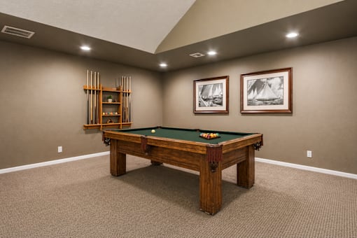 A pool table in a room with a wooden frame and a green felt cloth.