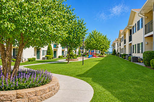 A residential area with a sidewalk and a grassy area.
