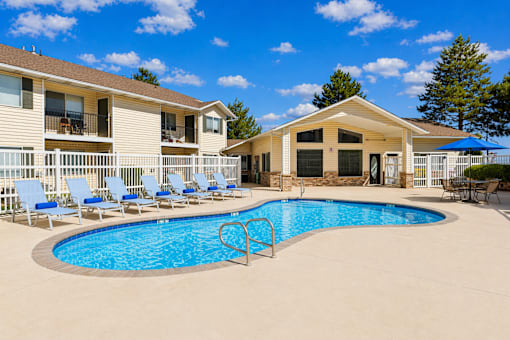 A swimming pool surrounded by lounge chairs and a building in the background.