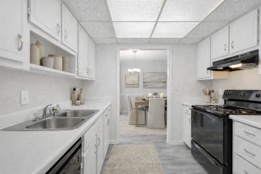 A kitchen with white cabinets and a black stove top oven.