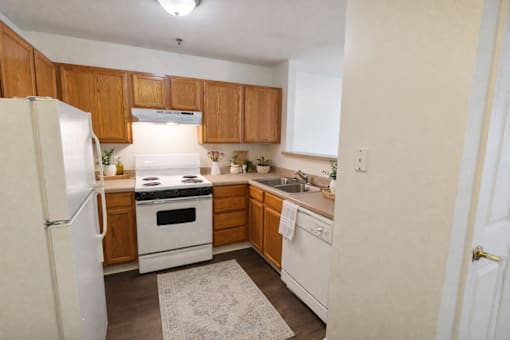 A kitchen with white appliances and wooden cabinets.