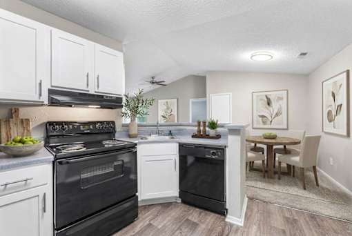 Modern kitchen with black appliances and dining area at Delta Crossing Apartments, Charlotte