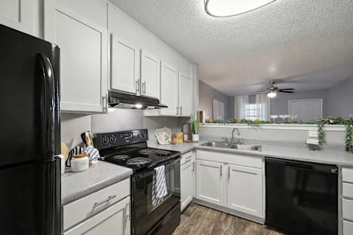 A black stove top oven sits in a kitchen with white cabinets.