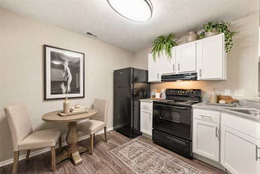 Modern kitchen with white cabinets and black appliances at Delta Crossing Apartments, North Carolina