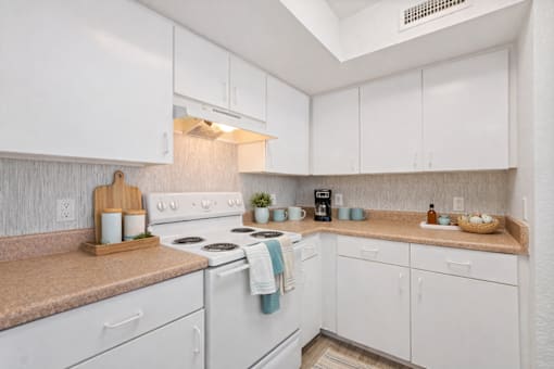 A kitchen with white cabinets and a white stove top oven.