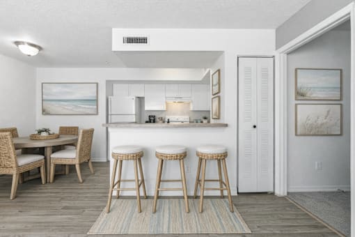 A kitchen with a bar area and a dining table with chairs.