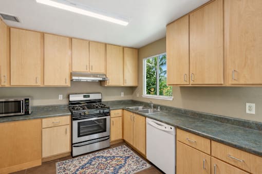 A kitchen with wooden cabinets and a stainless steel dishwasher.