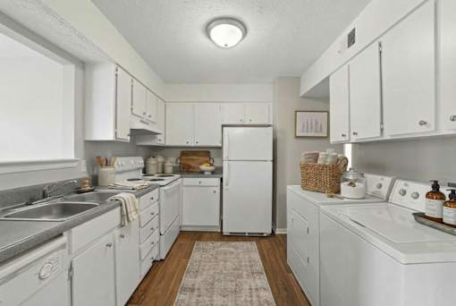 A white kitchen with a refrigerator, sink, and oven.