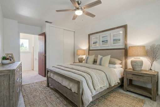 A bedroom with a bed, nightstand, and a ceiling fan.
