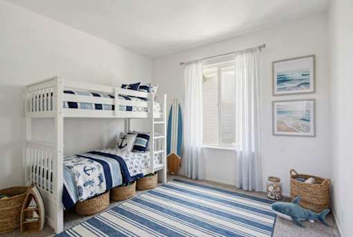 A room with two bunk beds and a striped rug.