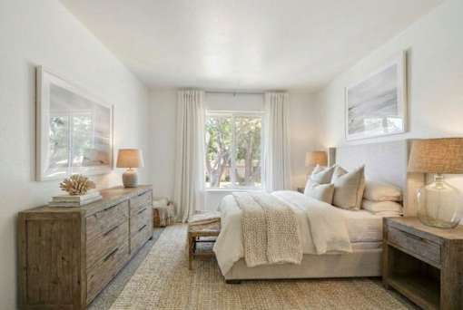 A bedroom with a bed, nightstand, and a window with curtains.