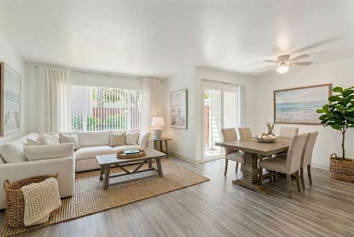A living room with a white couch, a wooden coffee table, and a dining table with chairs.