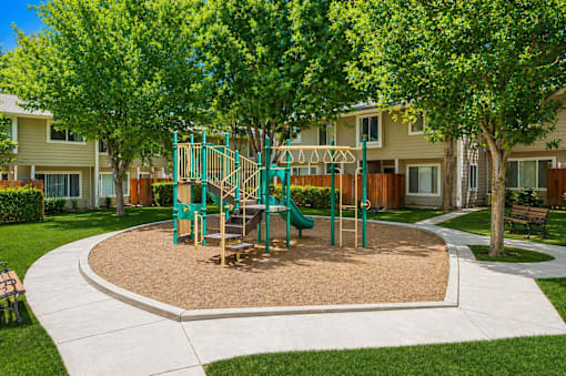 A playground with a green slide and a brown sandbox.