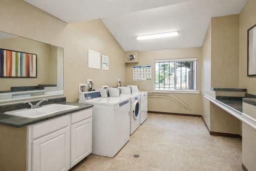 A laundry room with a washer and dryer, sink, and a calendar on the wall.