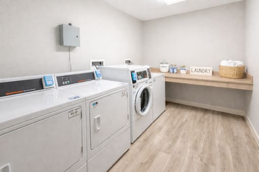 A laundry room with a washer and dryer, a basket of soaps, and a sign that says "Laundry".
