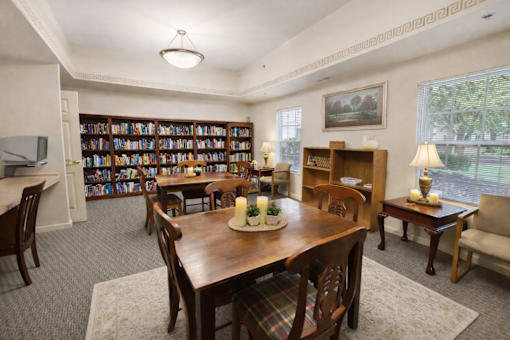A room with a large bookshelf filled with books and a table with chairs around it.