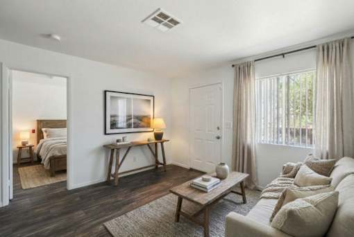 A living room with a couch, a coffee table, and a bed in the background.