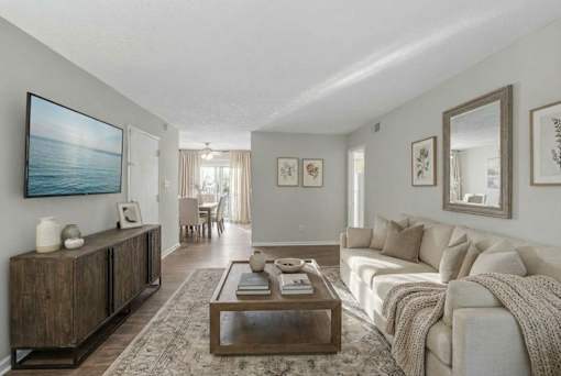 A living room with a couch, coffee table, and a painting on the wall.