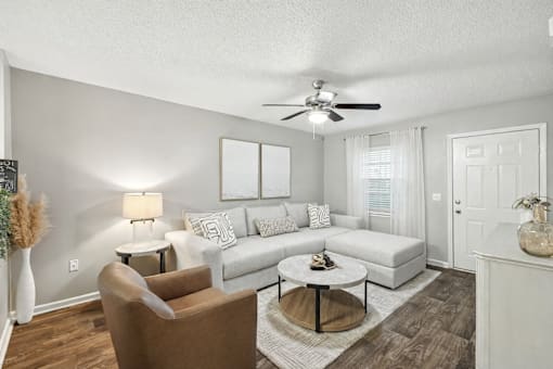 A living room with a brown chair, a white couch, and a ceiling fan.