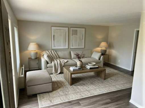 A living room with a grey sofa, a white armchair, a wooden coffee table, and two lamps.