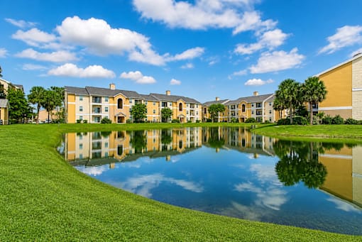 A large building complex is reflected in a pond.