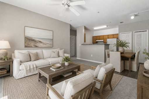 A living room with a white couch, a wooden coffee table, and a painting of a beach scene on the wall.