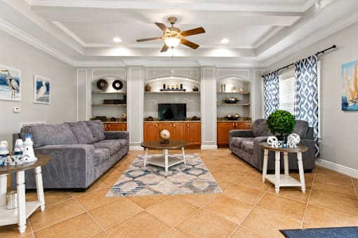 A living room with a grey couch, a coffee table, and a ceiling fan.