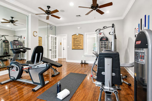 A gym with a variety of equipment including treadmills, weights, and a rowing machine.