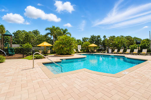 A large outdoor swimming pool surrounded by a brick patio.