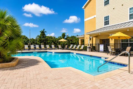 A large swimming pool surrounded by lounge chairs and umbrellas.