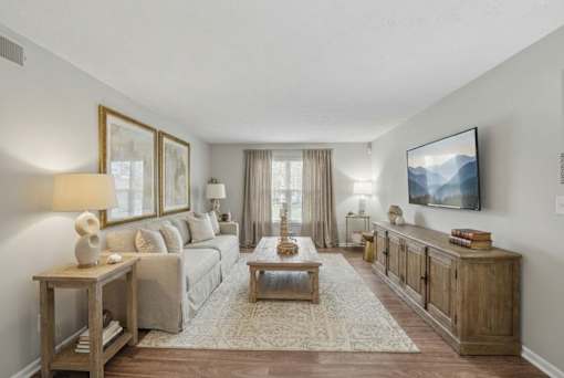 A living room with a couch, a coffee table, and a TV mounted on the wall.