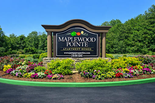 A sign for Maplewood Pointe Apartment Homes is surrounded by flowers.