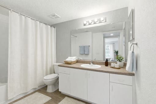 A white bathroom with a toilet, sink, and shower.