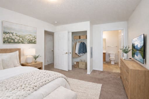 A bedroom with a large bed and a TV on the wall.