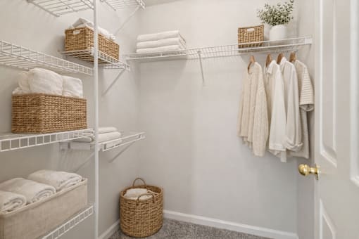 A white laundry room with towels and baskets on shelves.
