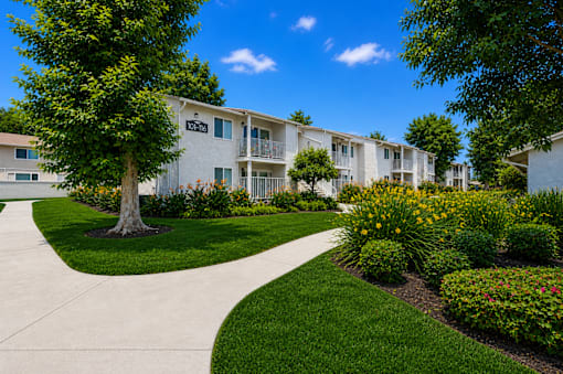 A white apartment building with a tree in front of it.